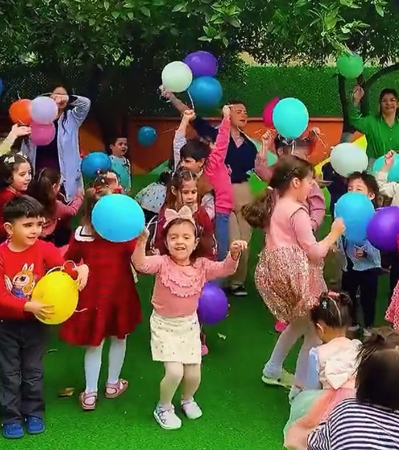 Bahçede rengârenk balonlarla dans eden çocuklar