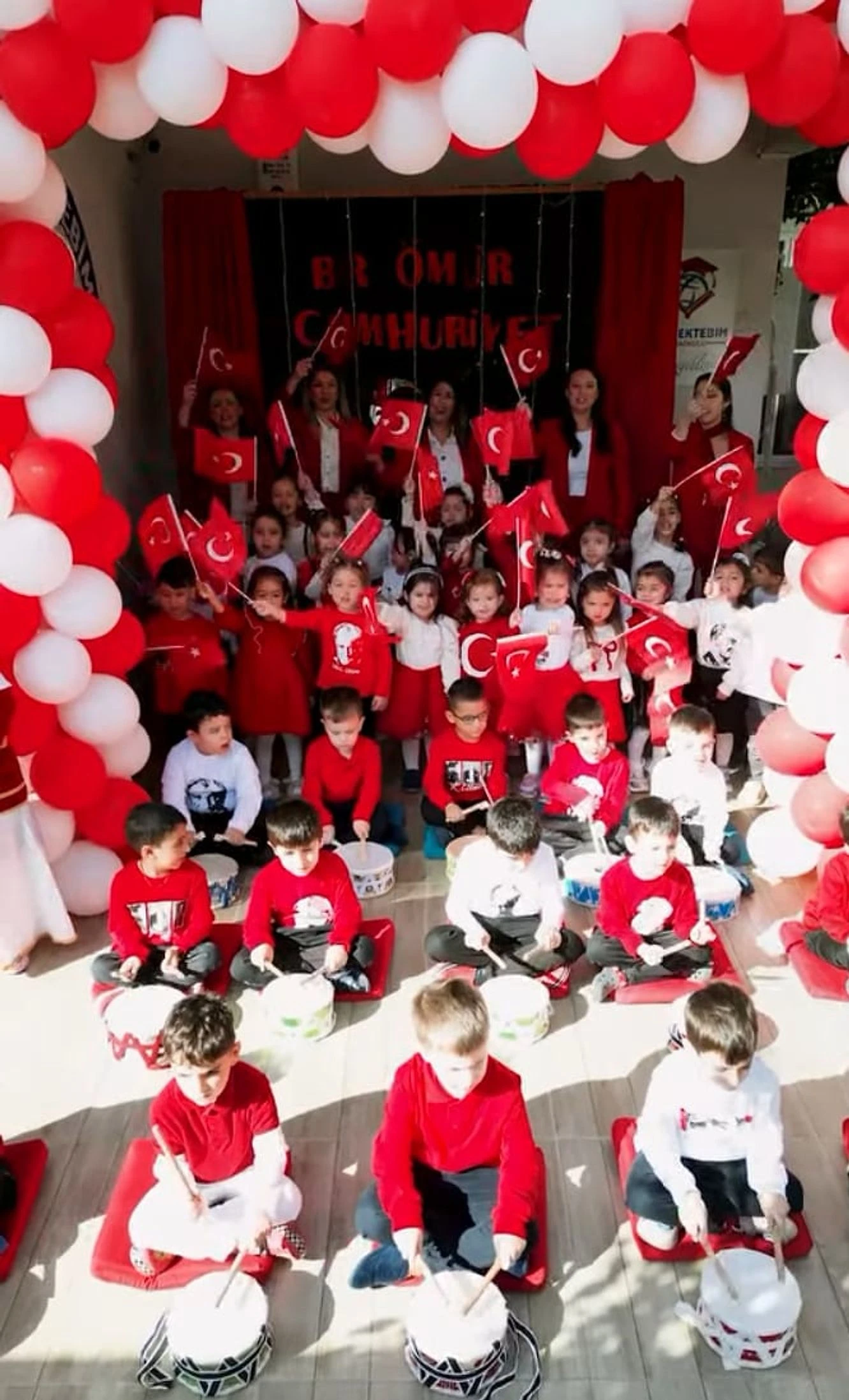Cumhuriyet Bayramı gösterisinde bayraklarla ve davullarla ritim tutan çocuklar